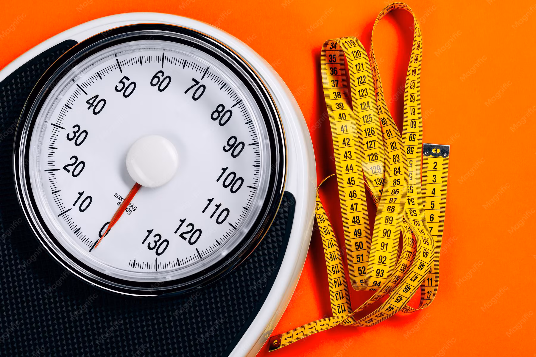 Bathroom scale and measuring tape on the floor, symbolizing realistic tracking