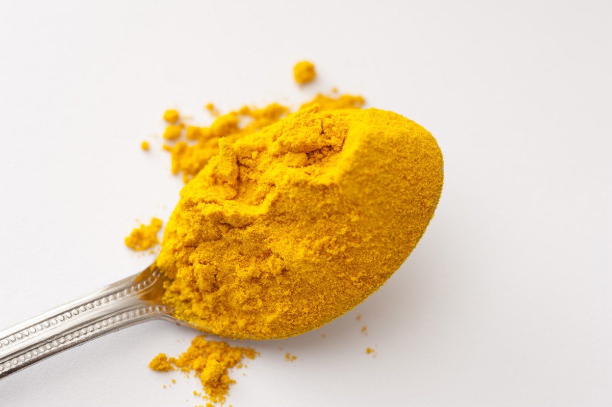Measuring spoons filled with turmeric powder on a wooden table.