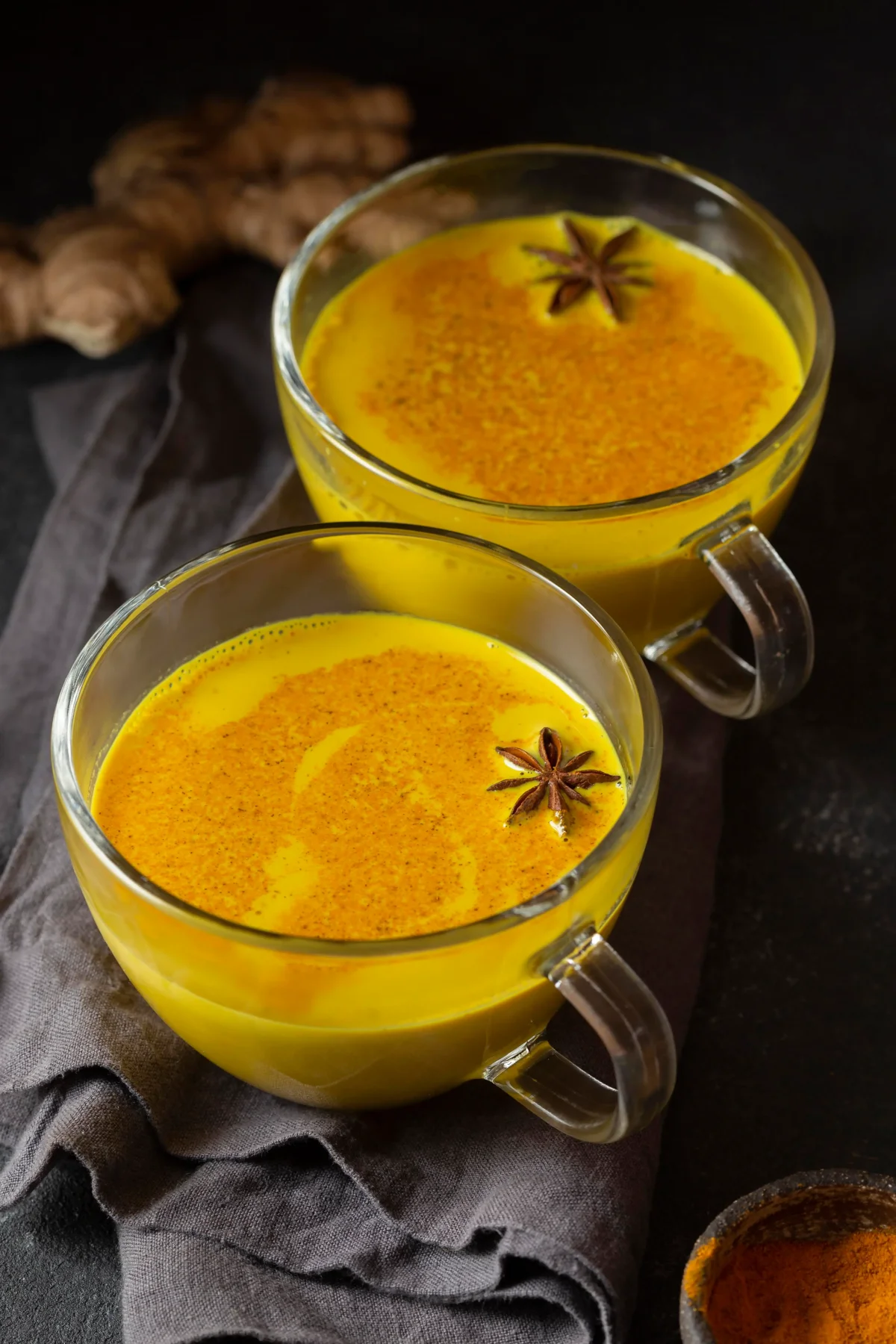 A woman journaling her weight loss progress with turmeric drinks and healthy snacks on the table
