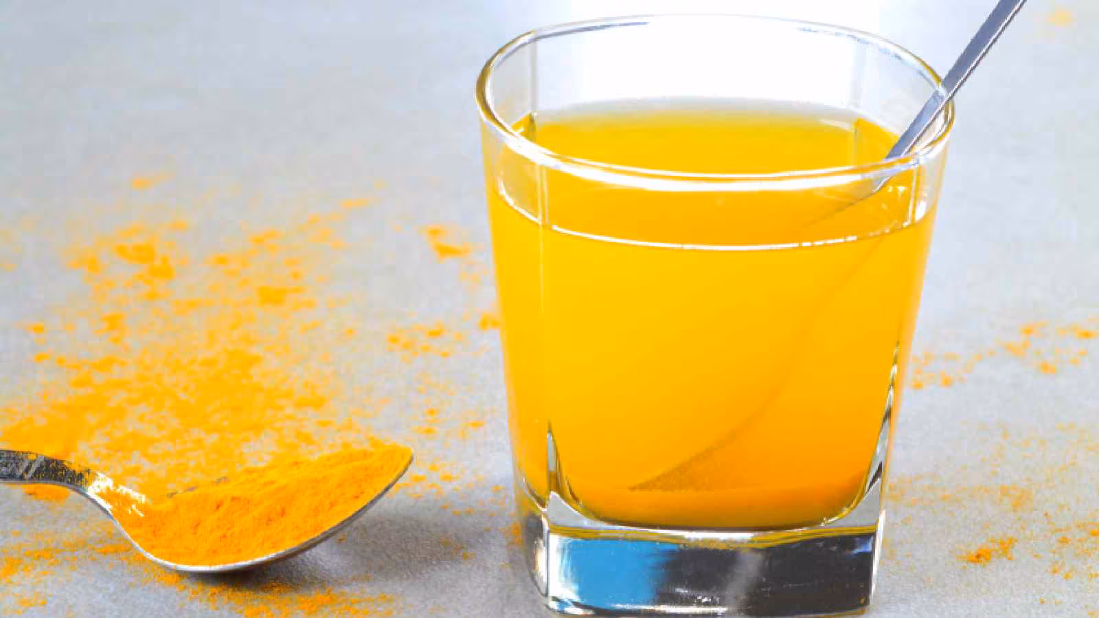 Glass of turmeric lemon water with slices of lemon on the side.
