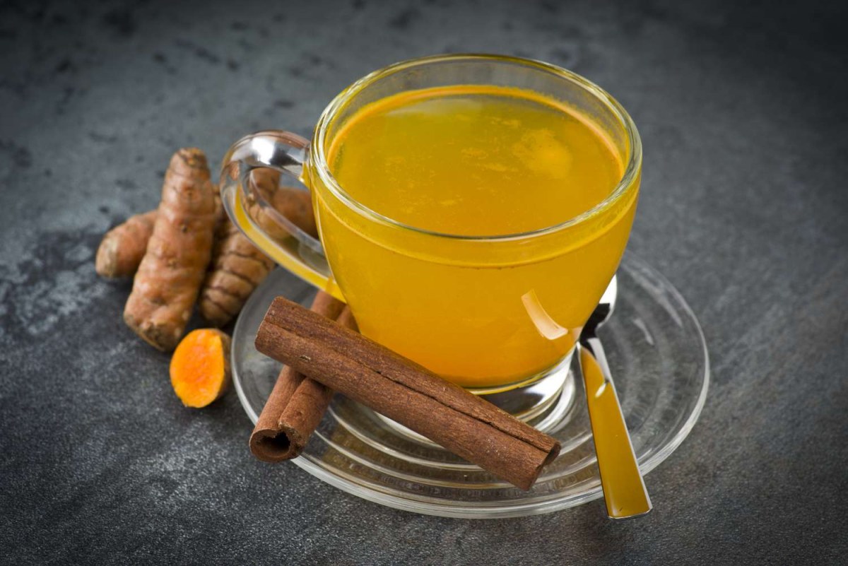 Person drinking turmeric tea in the evening while journaling on the sofa